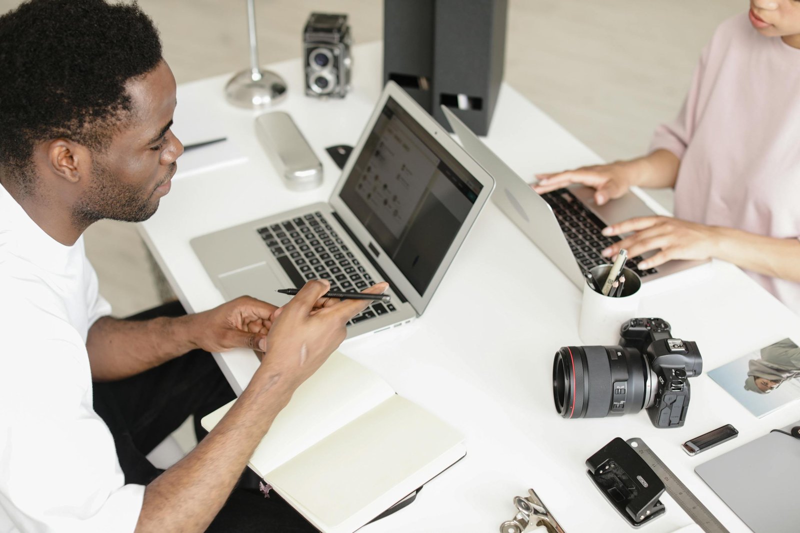 Two People using Laptop on White Surface